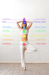 Young and healthy girl meditating in lotus position. Colored chakra lights over her body. Yoga,...