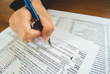 Naklejka premium Hand hold pen on sign point on the tax forms paper in business concept