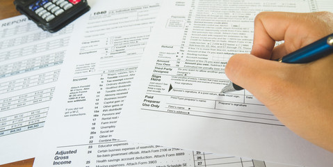 Obraz premium Hand hold pen on sign point on the tax forms paper in business concept
