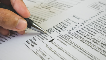 Fototapeta premium Hand hold pen on sign point on the tax forms paper in business concept
