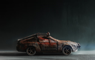 Post - apocalyptic handmade toy car on black background with smoke