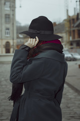 Fototapeta na wymiar Brunette woman in hat and coat at the street in Lviv