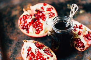 Pomegranate sauce in glass bottle over rustic background.