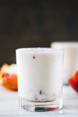 Traditional indian lassi - cold yougurt drink on white table with pomegranate seeds