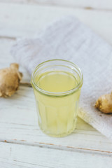 ginger juice in small glass jar with ginger root behind.