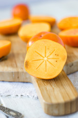 Half of persimmon fruit on wooden board.