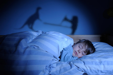 Kind schläft im Bett und träumt von Drachen und Ritter