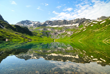 Mountain Lake with clean water in the Caucasus summer. Blue sky with white clouds.