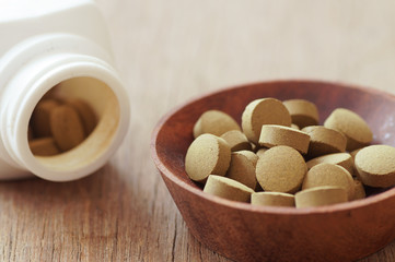 herb medicine in pill on wood background