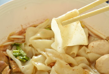 large rice noodle with braised pork in soup picking by chopstick