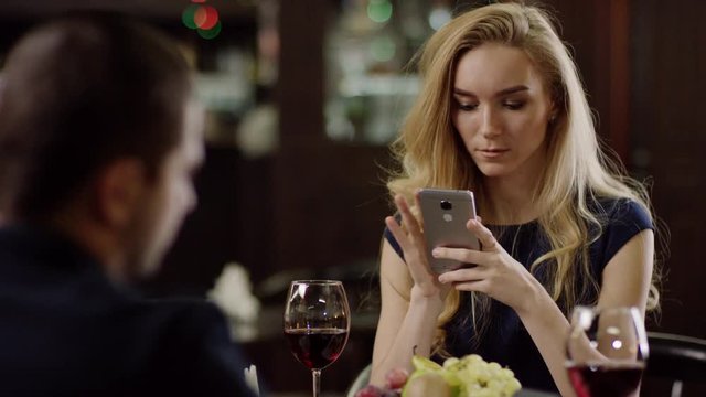 couple using smartphone during dating in pompous cafe