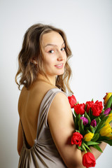 Feminine girl in a beige dress with flowers in their hands