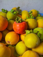 Ripe organic persimmon fruits in a pile at the local farmers market. persimmon background.