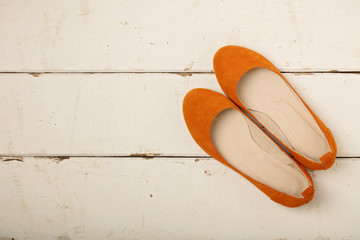 Orange women's shoes (ballerinas) on wooden background.