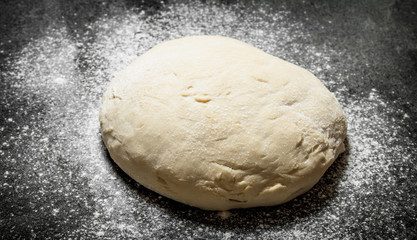 Dough background. Fresh dough with sifted flour on a rustic background.