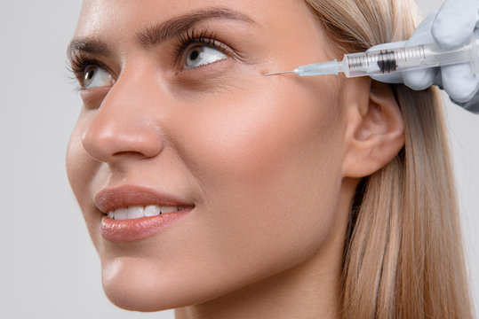 Cheerful young woman getting cosmetic injection