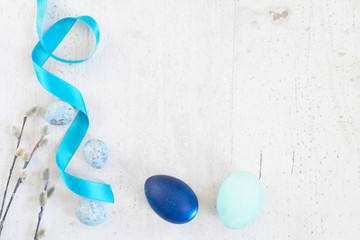 Blue easter eggs and catkins frame on white aged wooden tabletop with copy space
