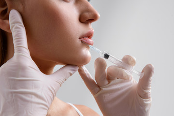 Surgeon injecting botox into lips of woman