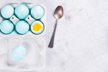 Set of blue easter eggs, one with yolk, spoon, top view on wooden aged table
