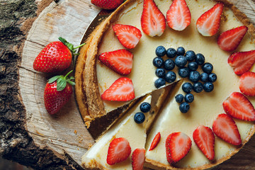 classic cheesecake new york with strawberry and blueberry on top in front of fireplace 