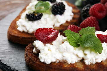 Bread with cheese cream and blackberries and raspberries for lunch table. Sharing antipasti on party or summer picnic time over wooden rustic background.