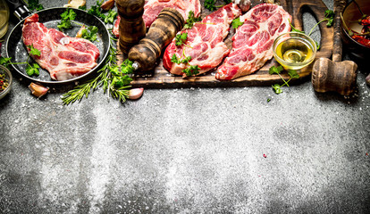 Raw meat background. Raw steak with herbs and spices on the old Board. On rustic background.