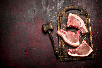 Raw meat background. Raw pork is with the old hammer.
