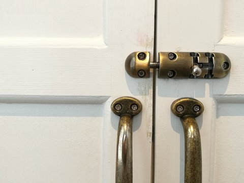 Modern vintage style door handle and slide lock on white natural wooden door, close up white door and lock