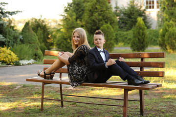 Brat i siostra uśmiechają się, siedząc na ławce w parku. - obrazy, fototapety, plakaty