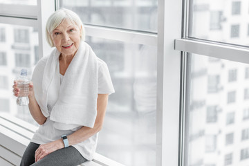 Healthy mature lady drinking water after exercising
