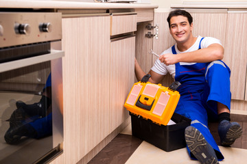 Young repairman working at the kitchen