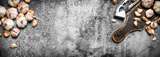 Spicy garlic press tool. On rustic background.