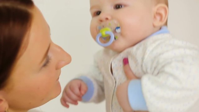 mother holding son with a pacifier on a white background