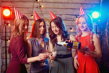 Fototapeta na wymiar Girlfriends birthday party pour champagne into glasses.