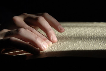 blind reading text in braille. close-up of human hands reading braille