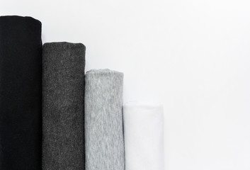 stack of black, grey and white (monochrome) t-shirt rolled up on white background, copy space