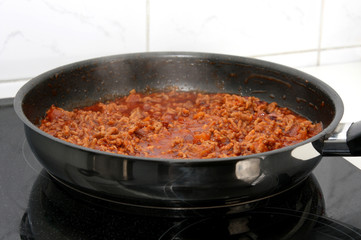 preparation sauce bolognese: mincemeat, onion and garlic in frying-pan on stove