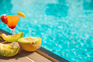 Cold cocktail near the pool in summer time with strawberry and orange
