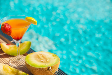 Cold cocktail near the pool in summer time with strawberry and orange