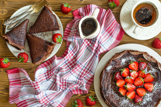 Chocolate pancakes with sauce and strawberries for breakfast