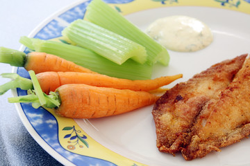 decorated plate with fried fish: river trout filet with carrots, celery and sauce, served