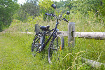 Fototapeta na wymiar Electric bicycle on the wood fence in the park on sunny summer day. Shot from the side. Unfiltered, with natural lighting. The view of the e motor, power battery and gear.