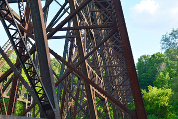 Metal rusty brown rail road bridge debris from below. Railway across the river in the park on steel bridge.