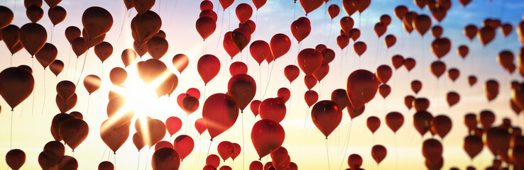 Rote Luftballons im Abendhimmel mit Sonne