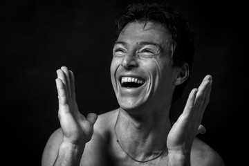 Close up portrait of hard laughing  man. Isolated on black background . Black and white picture