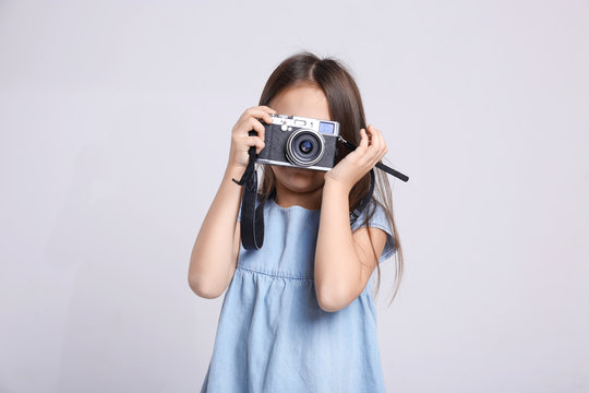 Little girl with vintage camera on light background