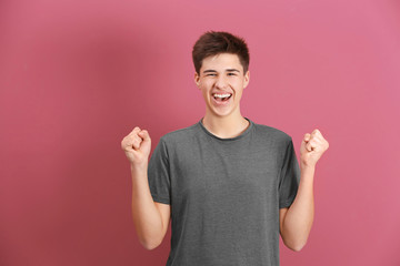 Happy teenage boy in casual clothes on color background