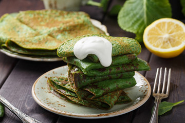 pancakes with spinach and sour cream on wood table
