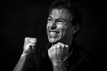 Close up portrait of isolated angry man. Monochrome picture, black background