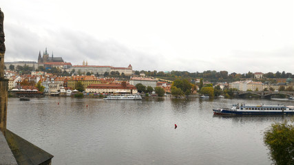 Fototapeta na wymiar Prague, Czech Republic - October 8, 2015 : Charles Bridge view on Vltava river, boats, residence, buildings, city and Old town. Mobile photo. Famous tourist and traveler routs.